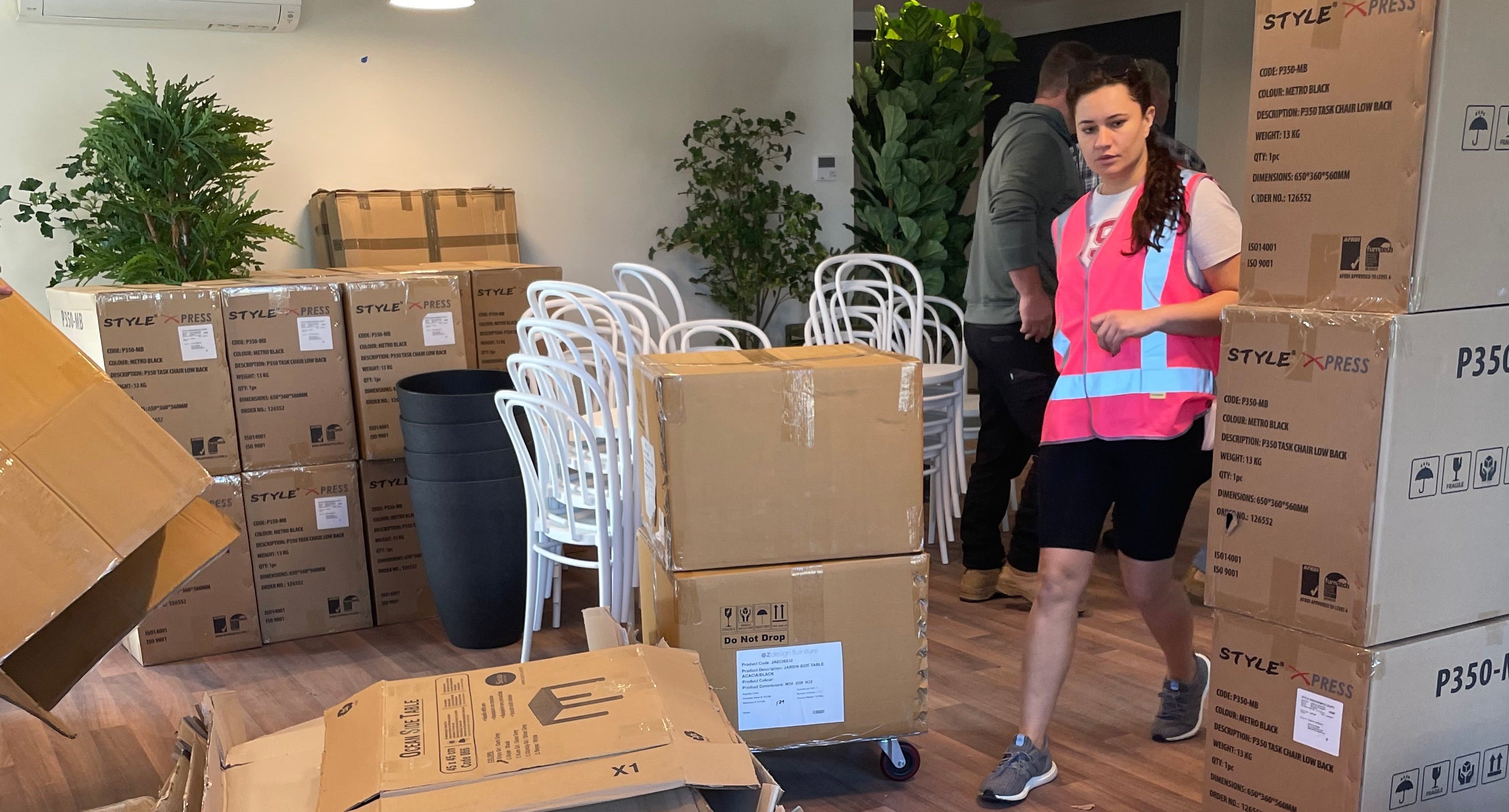Person in a warehouse setting with boxes and office chairs.