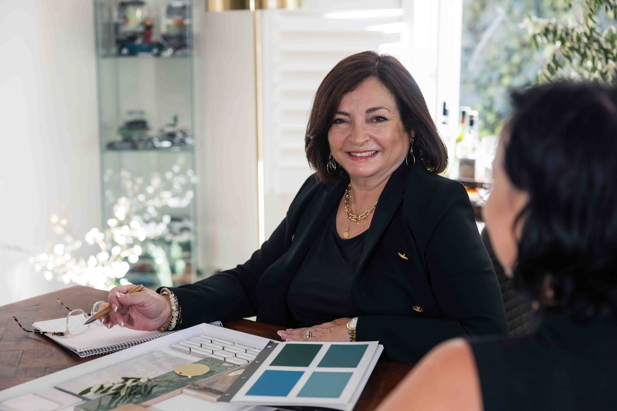 Designer discussing an interior project at a table with a notebook and colour samples.